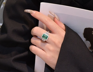 Close-up of emerald cut green gemstone ring with micro-pave diamonds on hand