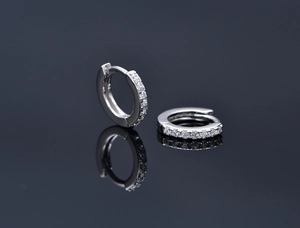 Macro shot of silver sterling earrings with micro-pave white crystals on gray reflective background