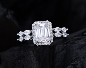 Macro detail of emerald cut white stone ring with marquise diamond band on dark stone