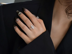 Silver cross ring on finger with emerald cut and round cubic zirconia stones