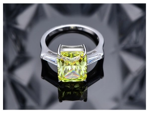 Detalle macro de anillo con piedra verde manzana corte radiant y piedras laterales trapecio