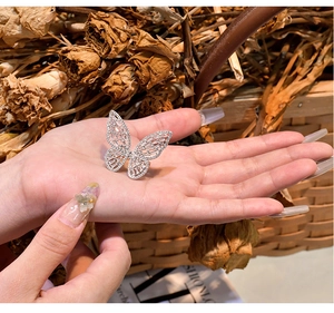Detailed view of wide butterfly silver ring with intricate hollow wings and zircons