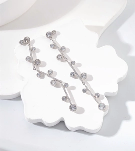 Detailed view of silver tassel earrings with sparkling crystals on a white plaster tray