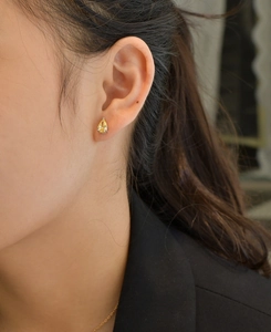 Close-up of a pear-cut yellow gemstone earring worn by a model in a black blazer