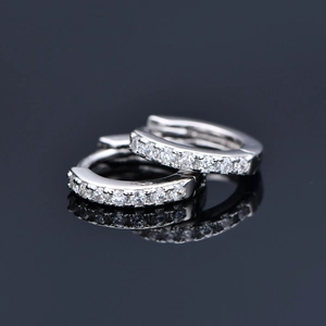 Minimalist sterling silver hoop earrings with clear cubic zirconia on a reflective surface