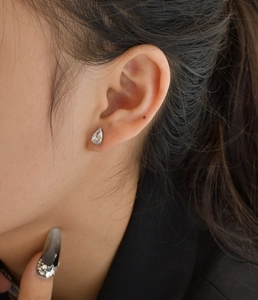 Close-up of elegant pear-shaped diamond stud earrings worn on model's earlobe