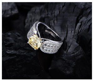 Makroaufnahme von gelbem Kissen-Smaragd-Diamantring auf Holzkohle-Hintergrund