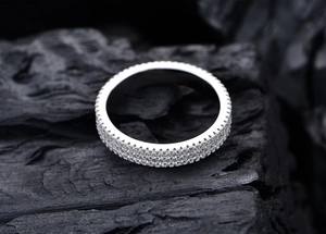 Macro shot of 925 sterling silver three-row pavé ring on a textured dark background