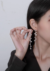 Macro view of long silver tassel earrings with round cubic zirconia on a model