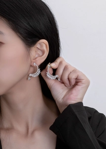 Macro detail of silver feather earrings with sparkling marquise zirconias on model