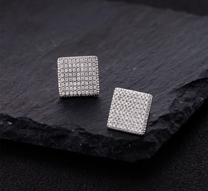 Macro detail of square micro-pave cubic zirconia earrings on dark textured stone