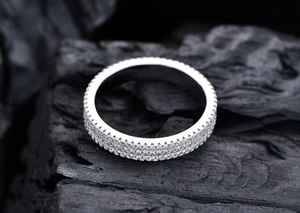 Macro shot of 925 sterling silver three-row diamond eternity ring on dark stone texture