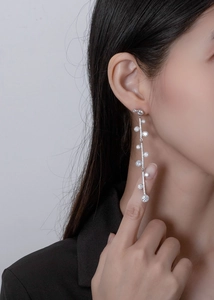 Macro detail of long silver tassel earrings with sparkling cubic zirconia on model