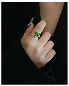 Dettaglio dell'anello con pietra verde taglio smeraldo e pavé di diamanti sulla mano