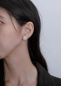 Macro view of square S925 silver stud earrings with pavé crystals on a female model