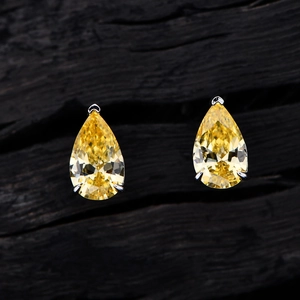 Elegant pair of pear-cut yellow carbon diamond S925 silver stud earrings on wood