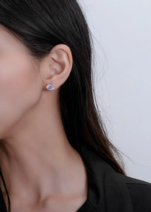 Detailed close-up of 8mm six-prong round cut silver stud earring on a female ear