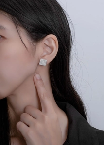 Macro view of square stud earrings with pave-set sparkling cubic zirconia on model's ear