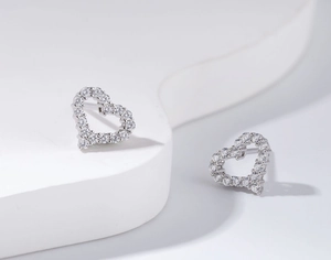 Macro shot of silver heart studs with pavé-set cubic zirconia on a minimalist base