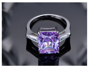 Vista macro de anillo con gema púrpura talla radiant de 10,5 ct sobre fondo negro pulido