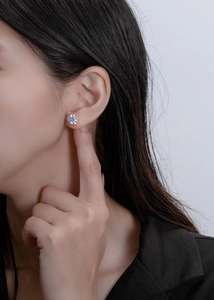 Close-up of a model wearing an 8mm six-prong solitaire stud earring with a silver finish
