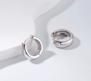 Detailed macro view of S925 sterling silver huggie earrings with sparkling cubic zirconia