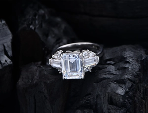 Close-up of S925 sterling silver ring featuring an emerald cut stone on a dark background