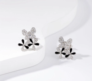 Detailed macro view of S925 silver butterfly and floral stud earrings with black enamel petals
