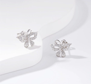 Macro shot of silver butterfly earrings with pavé set white crystals on geometric stand