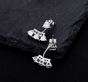 Close-up of S925 silver stud earrings with heart-cut stones on a dark stone surface