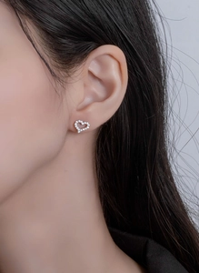 Close-up of S925 silver heart stud earrings with cubic zirconia on a model