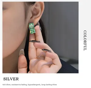 Close-up of 925 silver stud earrings with double square-cut green ice-cut gemstones