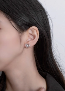 Close-up of elegant silver butterfly stud earrings with diamonds on a female model
