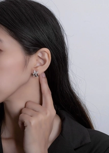 Detail of silver butterfly petal earring with zircons worn on model ear