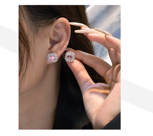 Close-up of pink Asscher cut halo earrings in silver setting shown being worn