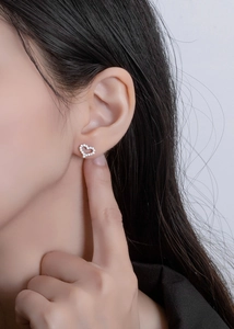 Close-up of sparkling heart-shaped cubic zirconia stud earrings worn by a model