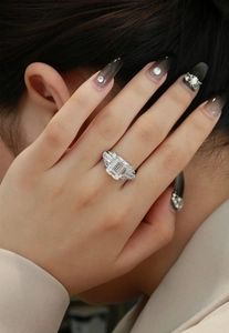 Detailed macro view of an emerald cut luxury silver ring worn on a model finger