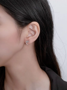 Close-up of S925 sterling silver crescent moon and star stud earring worn by model