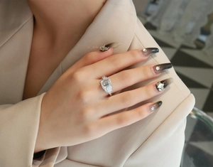 Detail view of emerald cut gemstone ring with baguette side stones on model's hand