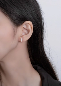 Close-up of minimalist S925 sterling silver lightning bolt stud earring with white zircons