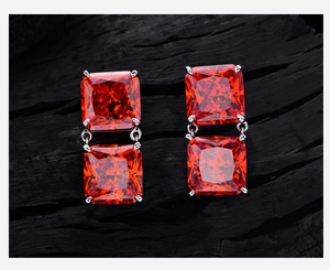 Close-up of 8ct square ice-cut orange zircon earrings with S925 silver setting on wood