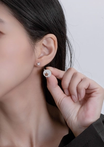 Close-up of asymmetric S925 silver star earrings with pavé zircons on a model's ear