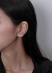 Macro view of crystal-encrusted fan-shaped earrings worn by a model in soft lighting