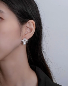 Close-up of a pearl crown earring featuring silver metal and sparkling zircons on ear
