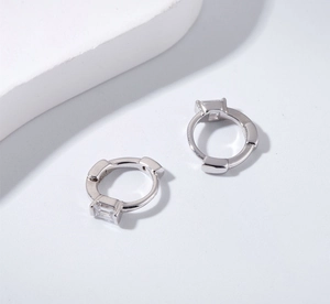 Detailed view of silver huggie earrings featuring four-prong set rectangular zircons