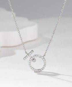 Close-up of minimalist silver pendant featuring pavé-set zircons and a moving bead