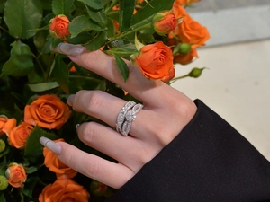 Close-up of snowflake micro-pave silver rings on hand with orange rose background