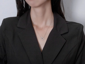 Close-up of a silver necklace with pavé zircon round and T-bar pendant on a model