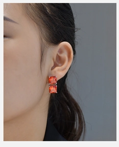 Detail of square orange gemstone earrings in S925 silver setting on a model