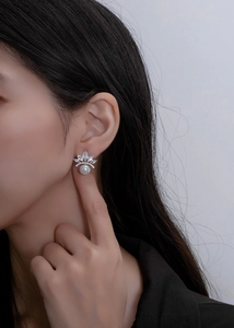Side view of model wearing a crown-shaped silver stud earring with white pearl and zircon